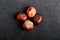 Four brown chestnuts on dark grey textile material background, top view with space for text around objects