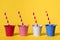 Four buckets on a yellow background with striped red and white straws