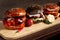 Four burgers on a light wooden board surface. Clouse-up.