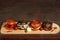 Four burgers on a light wooden board surface. For decoration are peppers and garlic.