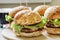 Four burgers on wooden plate with cola