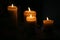 Four burning candles on black background