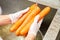 Four carrots washing at kitchen sink, close-up.