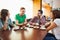 Four casual students having a cup of coffee chatting