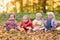 Four cheerful little baby sitting on yellow autumn