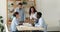 Four cheerful multiethnic businesspeople negotiating gather in office board room