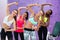 Four cheerful women holding dumbbells while doing exercises duri