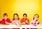 Four children paint Easter eggs at the table