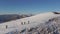 Four climbers walk on the ridge of a snowy mountain. People conquer the tops of winter mountains. Aerial view.