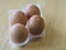 Four close up eggs in plastic stand on light wooden background