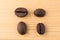 Four coffee beans in differen positions on wooden table