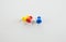 Four color push pin, yellow, red, white, and blue on white background