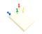 Four color push pins and yellow sticky note on isolated white ba