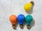 Four Colored Lightbulbs on a Marble Background