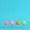 Four colorful golf balls with tee on bright blue background in pastel colors. Minimalism concept