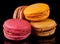 Four colorful macarons on black background