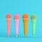 Four colorful microphones on bright blue background in pastel colors. Minimalism concept