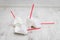 Four crumpled white paper cups with red tubes for coffee to go on white wooden table in selective focus