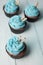 Four cupcakes with blue cream in brown paper form