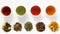 Four cups of tea on white table with large assortment of herbal, flower, berry