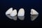 four dental crowns zirconia on a mirror table, black background. crowns for front teeth