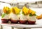 four desserts of apples, vanilla cream cream and cream decoration, slices of tangerine, green leaves