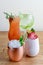 Four different assorted cocktail drinks made with alcohol and fruit served in unique cups and glasses on wooden table