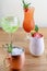 Four different assorted cocktail drinks made with alcohol and fruit served in unique cups and glasses on wooden table