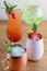 Four different assorted cocktail drinks made with alcohol and fruit served in unique cups and glasses on wooden table