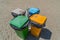 Four different coloured garbage cans stand at the beach