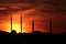 Four different minarets in silhouette on red sky with down sun and birds.