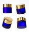 Four different views of frosted blue glass cream jar with gold cap, 3D render cosmetic product packaging isolated on