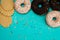 Four donuts, chocolate and with white cream and wafers lie in a semicircle on a wooden turquoise background