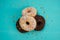 Four donuts, one on top of another, chocolate and white cream on a turquoise wooden background