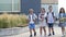 Four elementary school students, two boys and two girls, are walking around the school yard. The children are talking