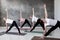 Four european women practicing yoga, Trikonasana pose.