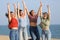 Four excited friends jumping raising arms on the beach