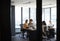 Four female creative colleagues busy working in an office, seen through glass wall with text on it