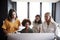 Four female creatives working around a computer monitor in an office, front view, close up