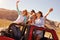 Four Female Friends On Road Trip Standing In Convertible Car