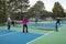 Four Female Pickleball Players Volley near the Net