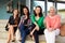 Four female teachers sitting on steps at entrance of school