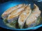 Four fresh salmon fillets frying in oil