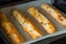 Four freshly baked baguette on baking tray in oven.