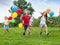 Four friendly glad kids running on green lawn