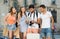 Four friendly travelers holding map in hands and looking for their way in european town