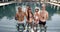 Four friends clinking with cocktails at swimming pool