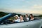 Four friends going for drive, sitting in silver cabriolet.