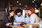 Four friends sitting at a cafe bar having a conversation looking at tablet. Positive face expressions