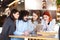 Four friends sitting at a cafe bar looking at tablet. Positive and smiling face expressions